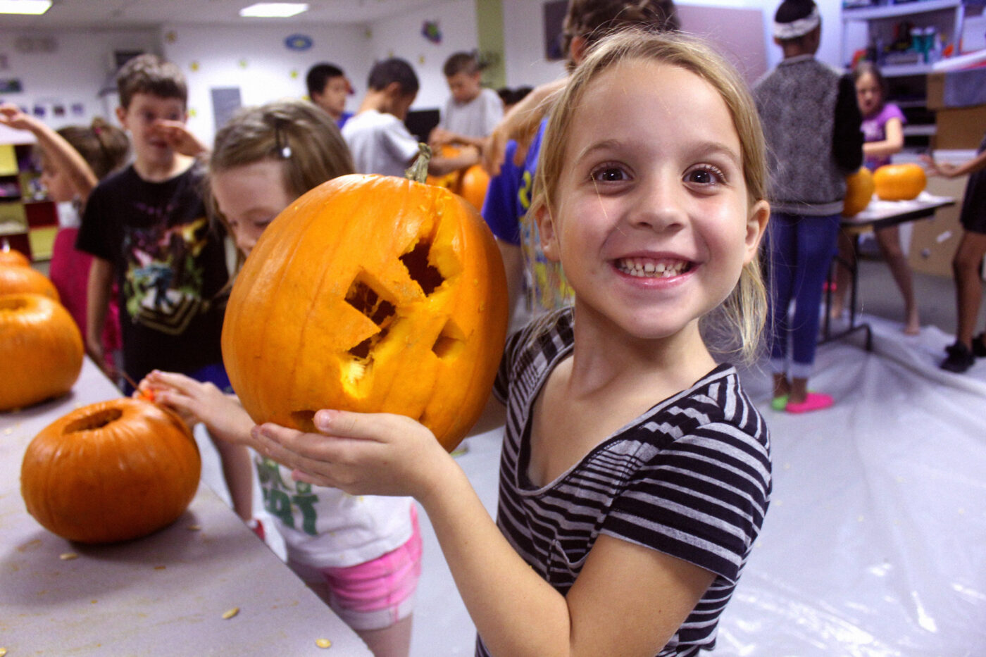 girl smiling at camera with jack-o-lantern