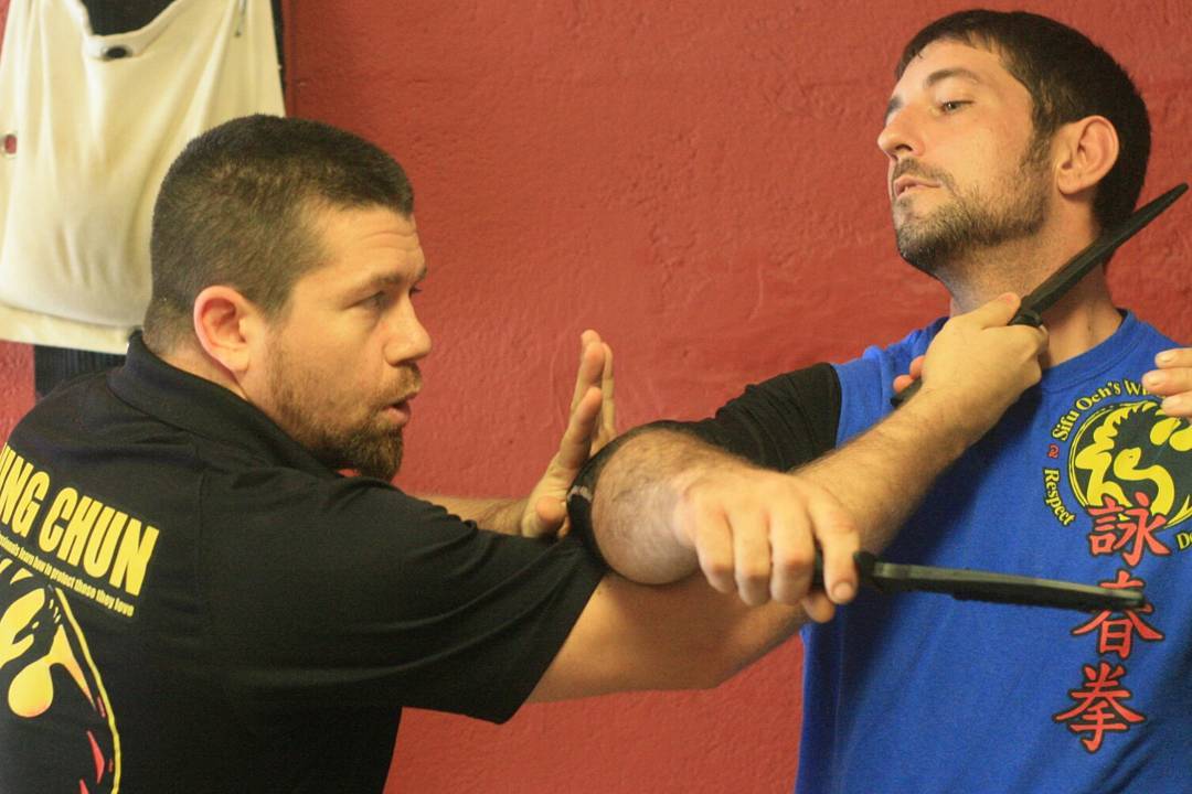 instructor teaching realistic self defense classes with knife techniques with student